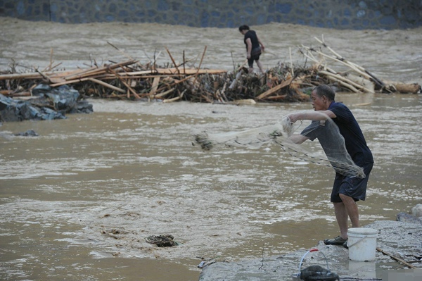 暴雨导致雷山洪水 灾民淡定洪水中捞鱼